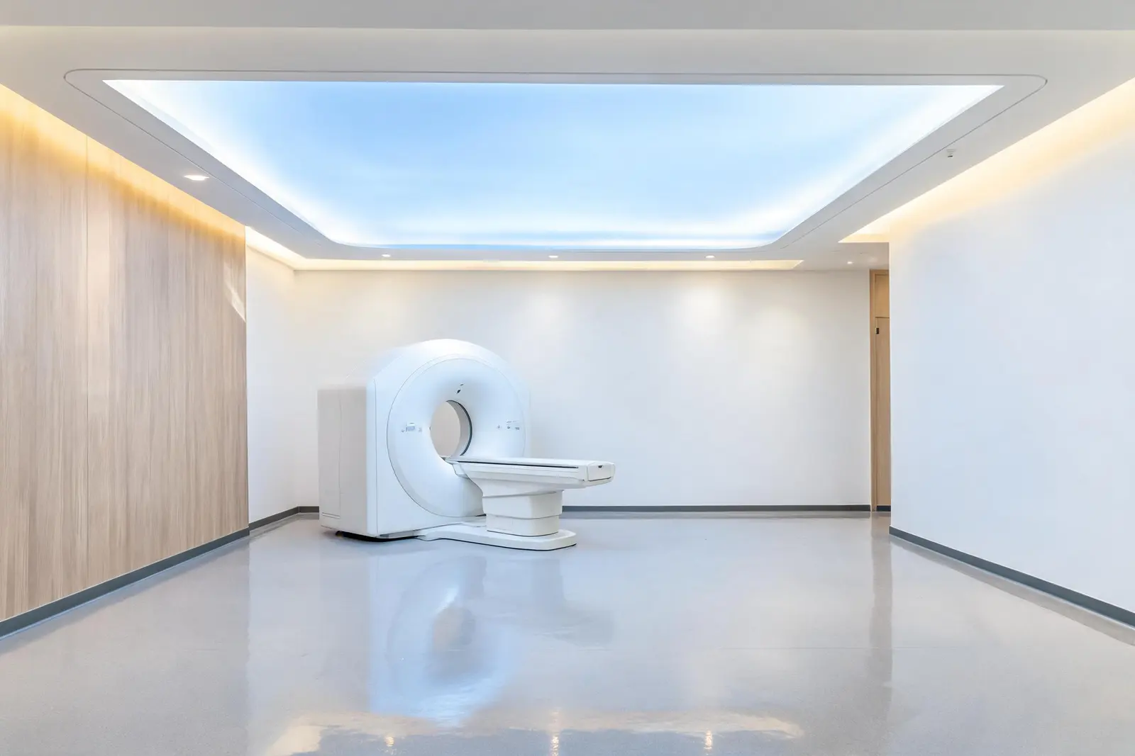 La sala di diagnostica per immagini di Nova Medical: una TAC bianca al centro, un ampio pannello luminoso a soffitto, una parete rivestita in legno chiaro e pavimento in resina lucida.
